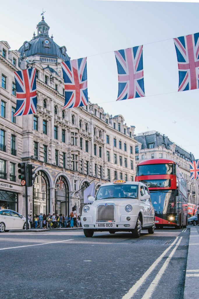 London's Oxford Street with a black cab and a red double-decker bus – a lively city street scene under Union Jack flags